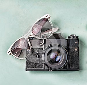 The concept: travel, vacation, active leisure, sea voyages. Ancient camera, sunglasses, old compass and starfish on a blue backgro