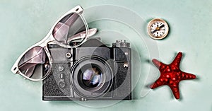 The concept: travel, vacation, active leisure, sea voyages. Ancient camera, sunglasses, old compass and starfish on a blue backgro