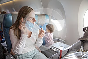 Concept trip with a child to Asia, fear of coronavirus covid-19. young beautiful mother in an airplane chair puts on a