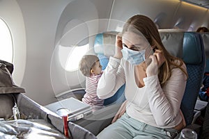 Concept trip with a child to Asia, fear of coronavirus covid-19. young beautiful mother in an airplane chair puts on a