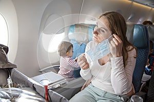 Concept trip with a child to Asia, fear of coronavirus covid-19. young beautiful mother in an airplane chair puts on a
