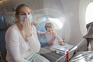 Concept trip with a child to Asia, fear of coronavirus covid-19. a young mother is sitting in an airplane chair in a medical