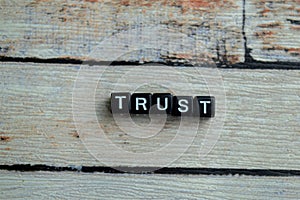 Concept of Trust written on wooden blocks. Cross processed image on Wooden Background