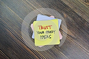 Concept of Trust Your Crazy Ideas write on sticky notes isolated on Wooden Table