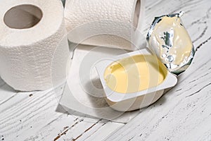 Pack of yogurt with tiolet paper on white wooden desk.