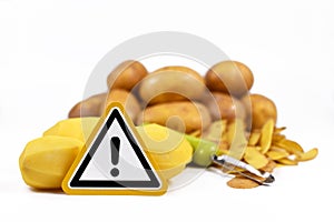 Concept for unhealthy or toxic substances in food like solanin or pesticide residues with warning sign in front of peeled potatos