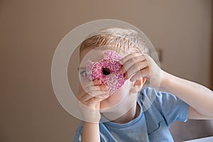 The concept is useless food. A little boy eats a pink doughnut at home and looks into the hole of the donation