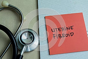 Concept of Uterine Fibroid write on sticky notes with stethoscope isolated on Wooden Table