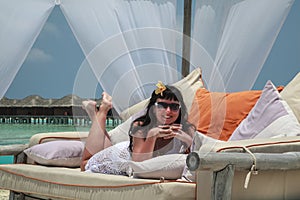 Concept of vacation. Beautiful brunette on a lounger in a Maldivian resort, The girl lies in a tent