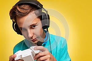 The concept of virtual and computer games. A portrait of teenage boy in a blue t-shirt and headphones, with a joystick in his