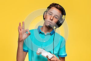 The concept of virtual and computer games. A teenage boy in a blue t-shirt and headphones, with a joystick in his hands,