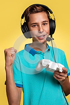 The concept of virtual and computer games. A teenage boy in a blue t-shirt and headphones, with a joystick in his hands, playing