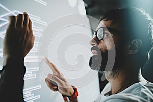 Concept of virtual panel display,diagram,digital graph interfaces.Young bearded man touching virtual panel with graphs