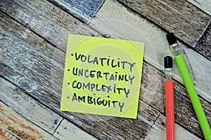 Concept of Volatility, Uncertainly, Complexity, Ambiguity write on sticky notes isolated on Wooden Table