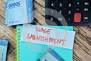 Concept of Wage Garnishment write on sticky notes with Indonesia Currency isolated on Wooden Table