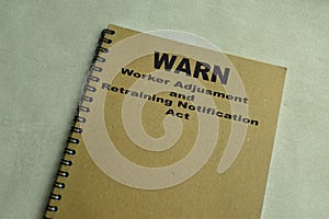 Concept of WARN - Worker Adjusment and Retraining Notification Act write on book isolated on Wooden Table photo