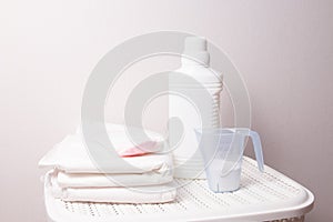 the concept of washing white linen, bleach and detergent on a white laundry basket