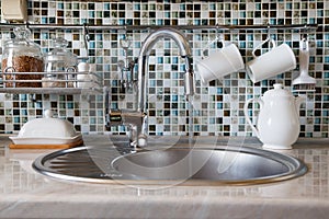 The concept of wasteful use of water. Open kitchen faucet spouting water. photo