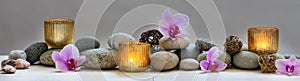 Concept of wellbeing with pebbles, orchids and candles, panoramic