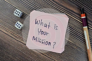 Concept of What is your mission? write on sticky notes isolated on Wooden Table