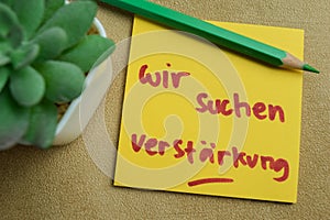 Concept of Wir suchen verstarkung write on sticky notes isolated on Wooden Table photo