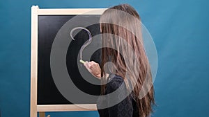 Concept Of Woman And Question Mark Drawn In Chalk On Blackboard. Female draws a question mark on the blackboard.