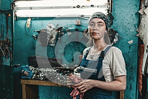 The concept of women`s equality and feminism. A woman in a work uniform wipes her hands with a rag. In the background, tools and