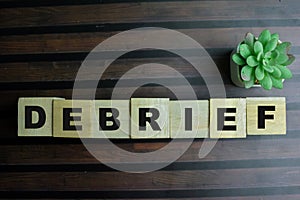 Concept of The wooden Cubes with the word Debrief on wooden background