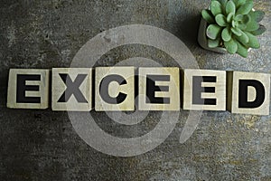 Concept of The wooden Cubes with the word Exceed on wooden background photo