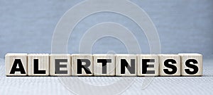 Concept word ALERTNESS on wooden cubes on a beautiful gray background