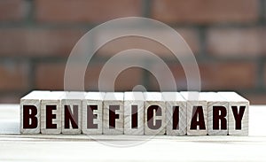 Concept word BENEFICIARY on cubes against the background of a brick wall