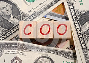 Concept word COO on wooden cubes on a beautiful background from dollar bills. Business concept