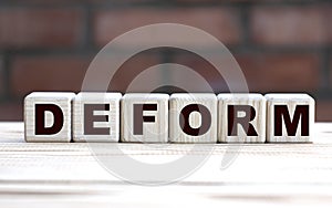 Concept word DEFORM on cubes against the background of a brick wall