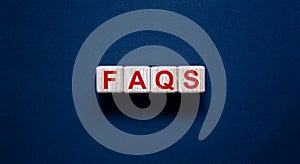 Concept word `FAQS` on cubes on a beautiful black background. Business concept, copy space