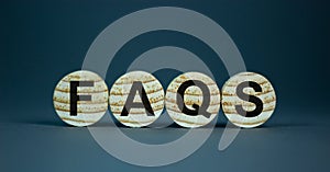 Concept word `FAQS` on wooden circles on a beautiful grey background. Business concept. Copy space