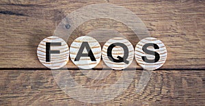 Concept word `FAQS` on wooden circles on a beautiful wooden  background. Business concept. Copy space
