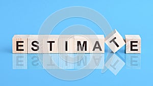 Concept word forming with cube on wooden desk background - Estimate. Blue background