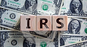 Concept word `IRS - Internal Revenue Service` on wooden blocks on a beautiful background from dollar bills. Business concept photo