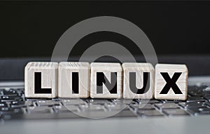 Concept word LINUX on cubes on the background of a laptop photo