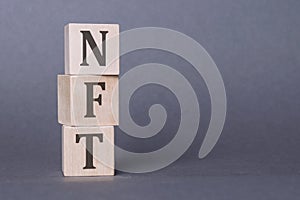 Concept word NFT on wooden cubes on a gray background. inscription on a financial, business or economic theme. NFT - short for Non