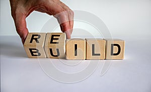 Concept word `rebuild` on cubes on a beautiful wooden table. Male hand. White background. Business concept. Copy space