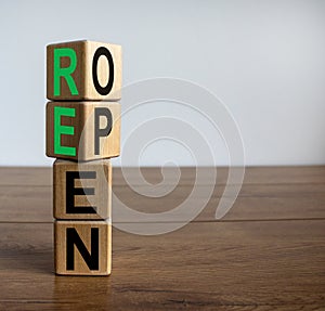 Concept word `reopen` on cubes on a beautiful wooden table. White background. Business concept. Copy space