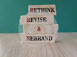 Concept word Rethink Revise and Rebrand on brick blocks. Beautiful wooden table, green background. Business brand motivational