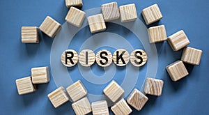 Concept word `risks` on woodwn circles on a beautiful blue background. Business concept