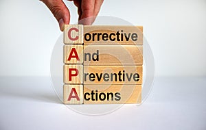 Concept words `CAPA, corrective and preventive actions` on cubes and blocks on a beautiful white background. Male hand. Business photo
