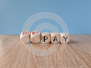 Concept words do not pay on cubes. Beautiful wooden table, blue background. Business, financial crisis and do not pay concept.