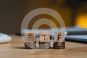 Concept words ETF wooden blocks on rows stack coins on the table, acronym ETF which refers to Exchange Traded Fund inscribed on