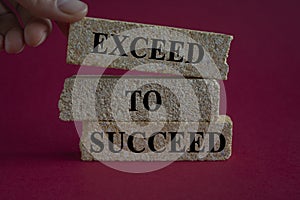 Concept words Exceed to succeed on beautiful brick blocks. Beautiful red background. Businessman hand. Business and exceed to