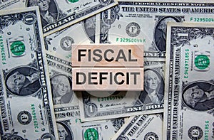 Concept words `fiscal deficit` on wooden blocks on a beautiful background from dollar bills. Business concept