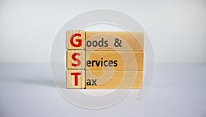 Concept words `GST, goods and services tax` on wooden cubes and blocks on a beautiful white background. Business concept. Copy